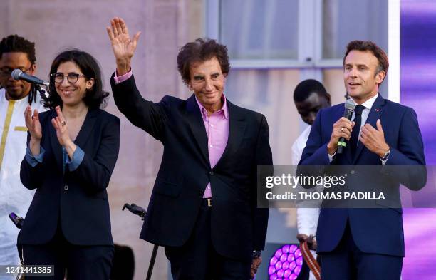 France's President Emmanuel Macron addresses the audience on stage next to French former Culture Minister Jack Lang France's Culture Minister Rima...