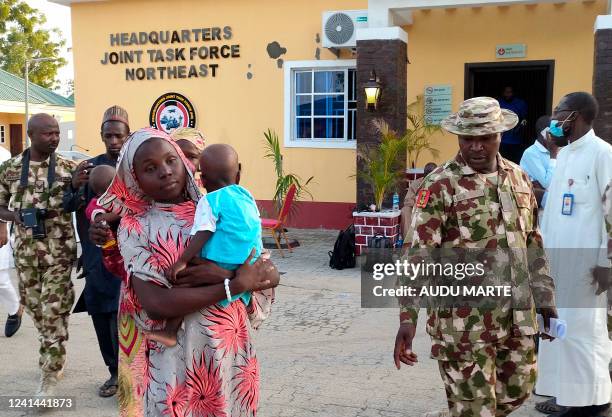 Kidnapped Chibok schoolgirl Hauwa Joseph carries a baby as she walks accompanied by soldiers to Maimalari Barracks in Maiduguri, northeast Nigeria,...