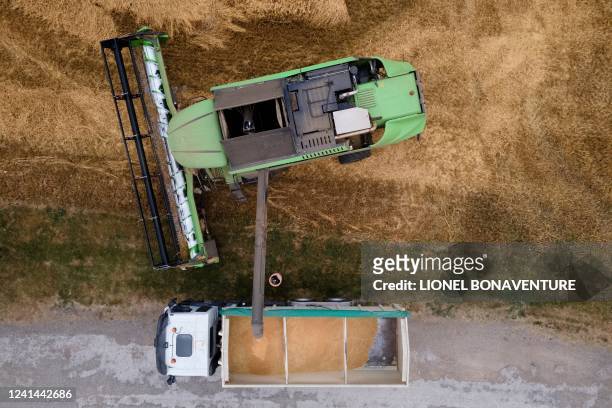This aerial photograph taken on June 21 shows a farmer driving a combine harvester in a wheat field in Sainte Foy d'Aigrefeuille, near Toulouse,...