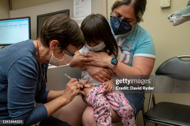 Deni Valenzuela receives her first dose of the Pfizer Covid-19 vaccination from nurse Deborah Sampson while being held by her mother Xihuitl Mendoza...