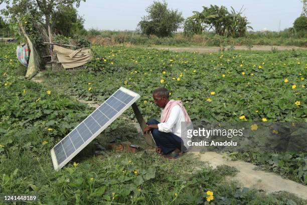 Indian man charging his phone through solar energy panel placed outside a temporary settlement along the Yamuna river in New Delhi on the World...