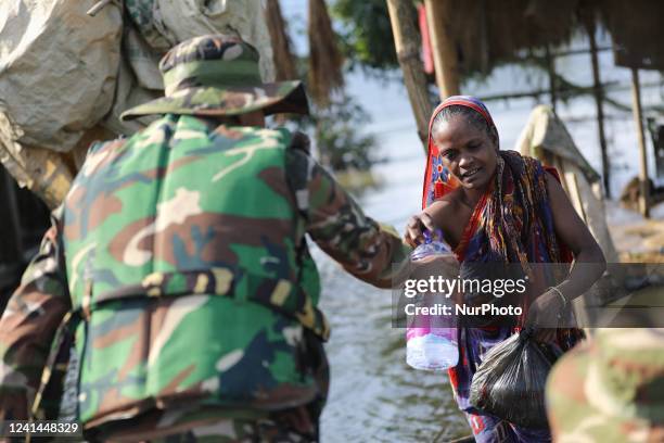 Woman l receives food aid from Bangladesh army in a flooded residential area following heavy monsoon rainfalls in Sylhet, Bangladesh on June 21,...