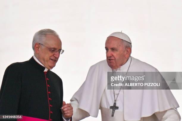 Prefect of the Pontifical House, Monsignor Leonardo Sapienza helps Pope Francis reach his seat as he arrives to hold the weekly general audience on...