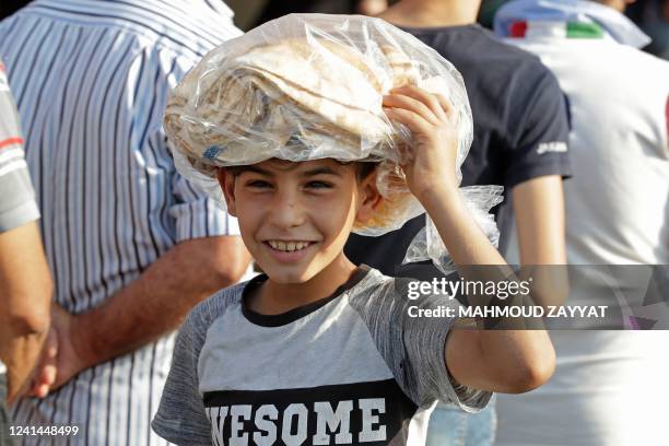 Young boy leaves a bakery with a bag of bread in Lebanon's southern city of Sidon on June 22, 2022 as fuel and wheat shortage deepens. - Lebanon has...