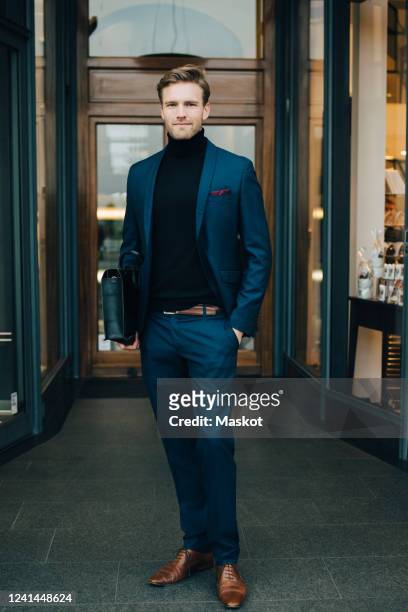 portrait of businessman with hands in pockets standing by store in city - formal portrait stock-fotos und bilder