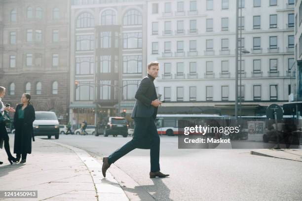 side view of entrepreneur walking on road against building in city - walking in street stock-fotos und bilder