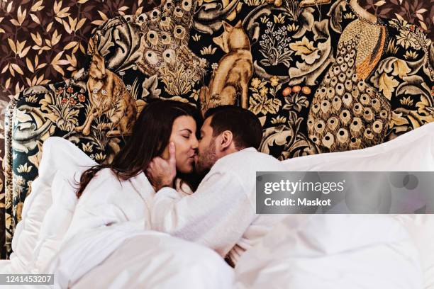 couple kissing while lying on bed in hotel room - man and woman cuddling in bed stockfoto's en -beelden