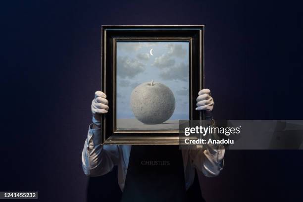 An art handler holds a painting titled âSouvenir de voyageâ by Rene Magritte during a photo call at Christie's auction house to present the...