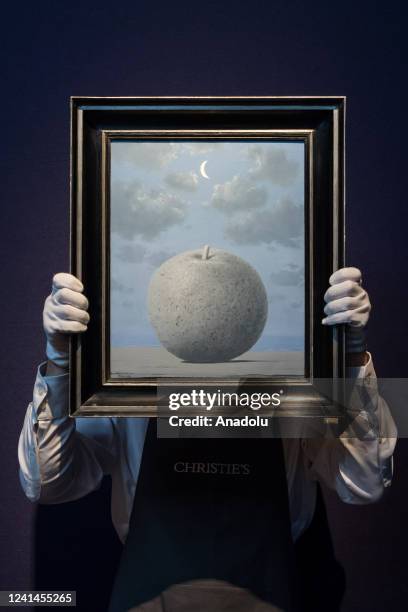 An art handler holds a painting titled âSouvenir de voyageâ by Rene Magritte during a photo call at Christie's auction house to present the...