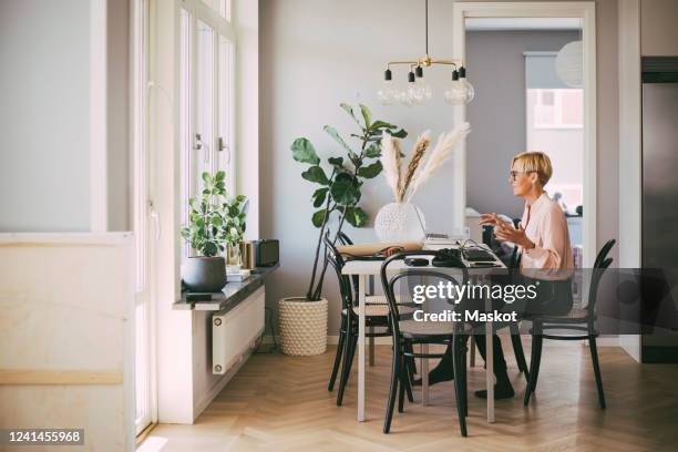 woman sitting at table having an online meeting working at home - conference dining table stockfoto's en -beelden