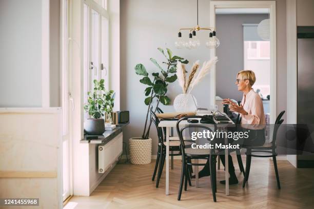 woman sitting at table having an online meeting working at home - conference dining table stock pictures, royalty-free photos & images