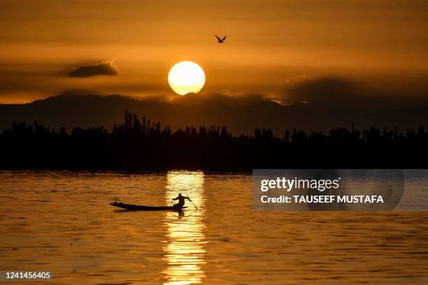Boatman steers a boat in the waters of Dal Lake after heavy rainfall in Srinagar on June 22, 2022.