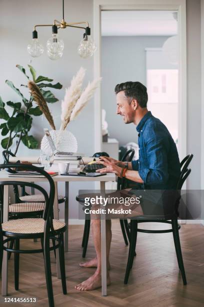 happy man sitting at table in underwear working at home having a video call - jock strap stock pictures, royalty-free photos & images