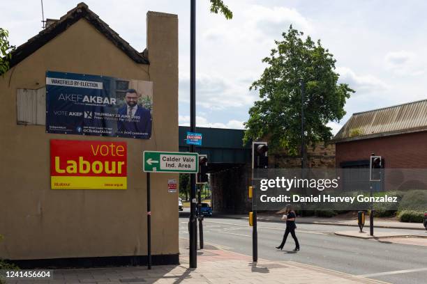 Member of the public makes their way past a vacant pub with several placards and signs campaigning for the Labour Party and an independent candidate...