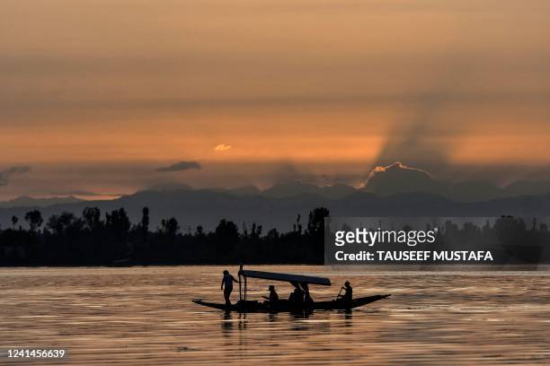 People travel on a boat in the waters of Dal Lake after heavy rainfall in Srinagar on June 22, 2022.