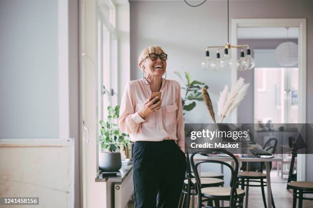 woman talking on the phone laughing at home - mid adult stock pictures, royalty-free photos & images