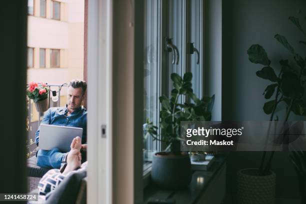 man working on laptop relaxing on balcony - balcony stock photos et images de collection