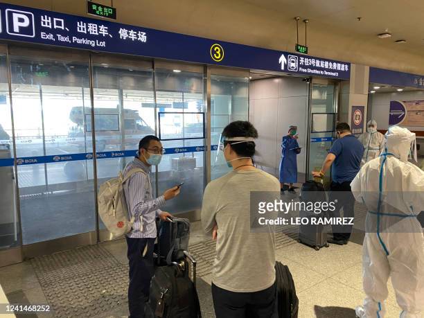This photo taken on June 18, 2022 shows inbound passengers waiting to be taken to quarantine-designated destinations from the Beijing International...