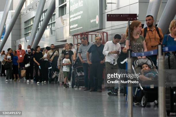 Travellers are seen waiting in a long line at a security check point at Duesseldorf airport in Duesseldorf, Germany on June 22, 2022 as staff...