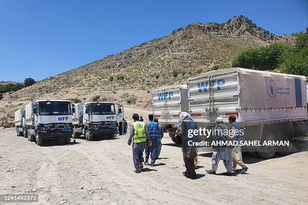 Men walk next to World Food Programme trucks with aid after an earthquake in Gayan district, Paktika province, on June 24, 2022. - Many survivors of...