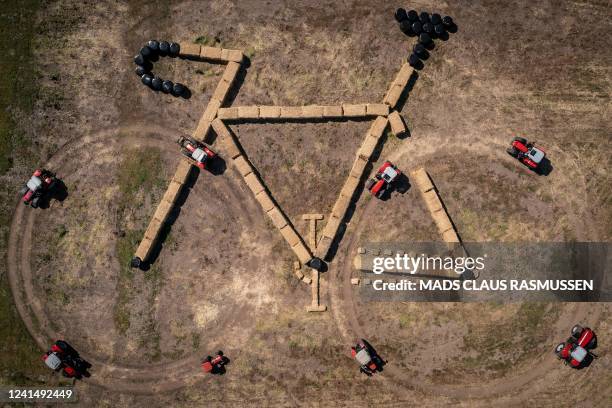 Aerial view taken with a drone on June 23, 2022 shows tractors and strawballs forming a bike-shaped land art sculpture along the route of the 3rd...