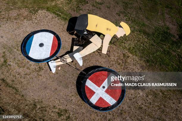 Aerial view taken with a drone on June 23, 2022 shows a land art work featuring a cyclist riding with the flags of France and Denmark on his wheels...