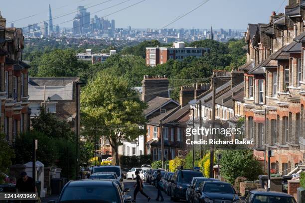 South London residential street with homes leading downhill towards the city in the distance, at Crystal Palace in south London, on 22nd June 2022,...