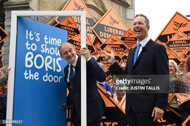 Britain's centrist Liberal Democrats party leader Ed Davey and newly elected MP Richard Foord unveil a makeshift door reading "It's time to show...