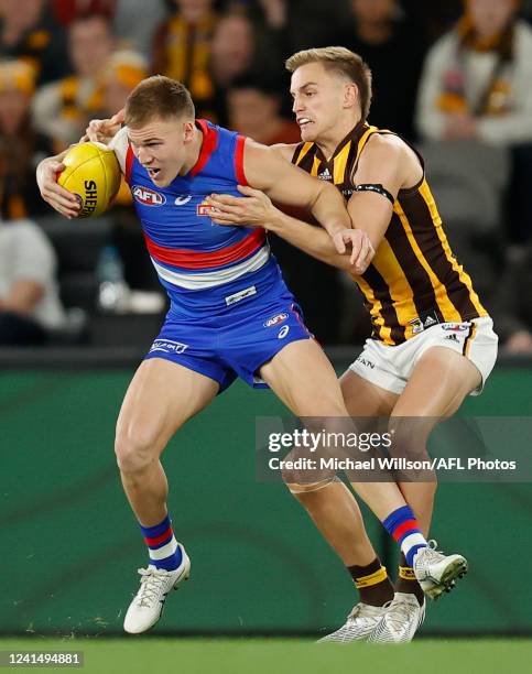 Robbie McComb of the Bulldogs is tackled by Harry Morrison of the Hawks during the 2022 AFL Round 15 match between the Western Bulldogs and the...