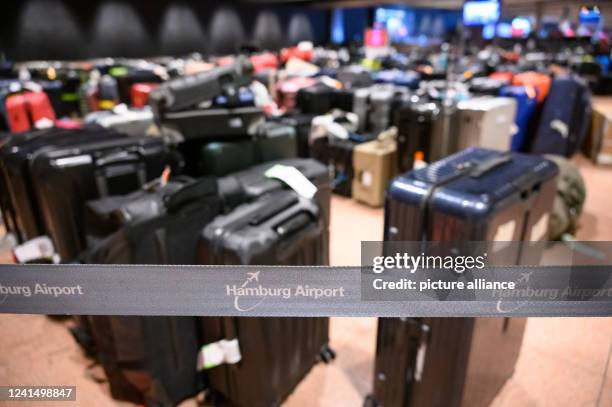June 2022, Hamburg: "Hamburg Airport" is written on a barrier tape in front of numerous stored suitcases in the baggage claim area. Hundreds of...