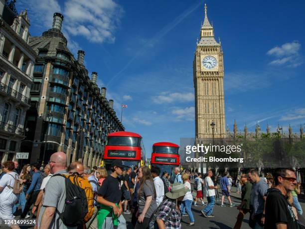 Pedestrians cross a road junction near Portcullis House, left, and the Elizabeth Tower, also known as Big Ben, in London, UK, on Monday, June 2022....