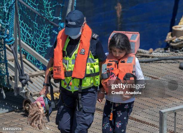 Child with a toy is escorted to the port as 50 migrants arrived on the shores of Kent, after travelling across the English Channel in Dover, United...