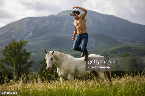 shirtless cowboy jumping from a horse in rural scene - taming horse stock pictures, royalty-free photos & images