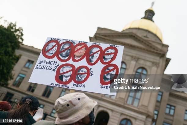 Man holds a sign supporting impeachment of Supreme Court justices to protest the Supreme Court's decision in the Dobbs v Jackson Women's Health case...