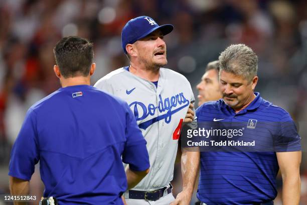 Daniel Hudson of the Los Angeles Dodgers is helped off the field after an injury during the eighth inning against the Atlanta Braves at Truist Park...