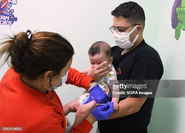 Adrian Perez looks on while a nurse administers a dose of the Moderna Covid-19 vaccine to his 6-month-old son at Nona Pediatric Center in Orlando. On...