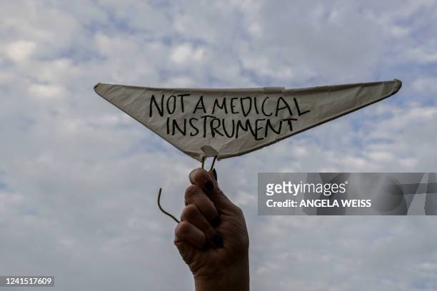 Person holds a metal coat hanger, a symbol of the reproductive rights movement, with the words "Not a Medical Instrument" as abortion rights...