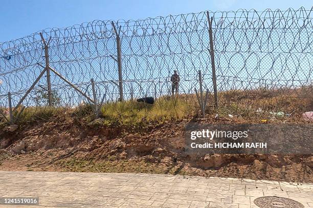 Picture taken on June 25 shows a member of the Moroccan security forces on the border fence separating Morocco from Spain's North African Melilla...