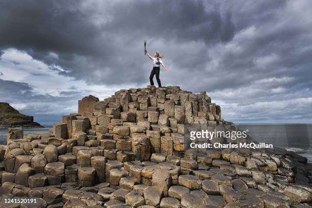 Batonbearer Lucy Walton holds the Queens Baton aloft during the Birmingham 2022 Queen's Baton Relay at a visit to the Giants Causeway on June 25,...