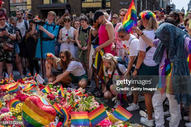 Flowers and rainbow flags are left along the street near a restaurant where two people were injured and at least 10 were injured when a man opened...