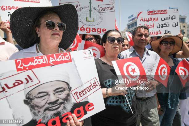 Supporters of the Free Destourian Party hold placards, flags of Tunisia and a poster of the founding chairman of the International Union of Muslim...