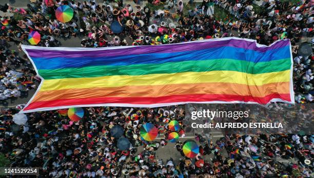 Aerial view showing people displaying a large banner in the colours of the Rainbow flag during the Pride Parade in Mexico City on June 25, 2022.