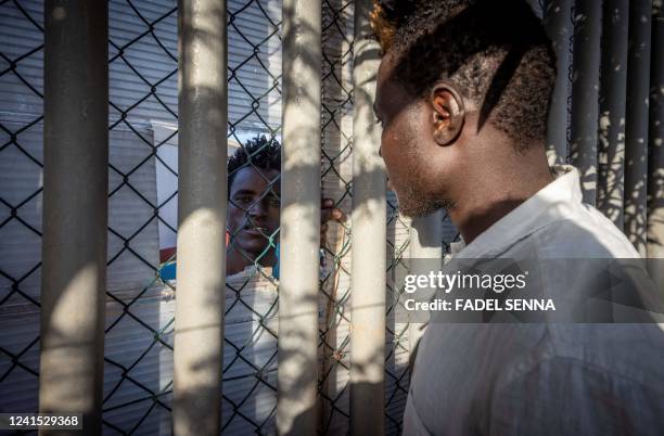 Migrant talks to a man through a fence in a temporary centre for migrants and asylum seekers on June 25, 2022 in Melilla, a day after at least 23...