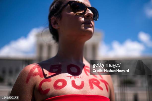 An abortion-rights activist with the words Abort the Court painted on her chest protests in front of the Supreme Court building following the...