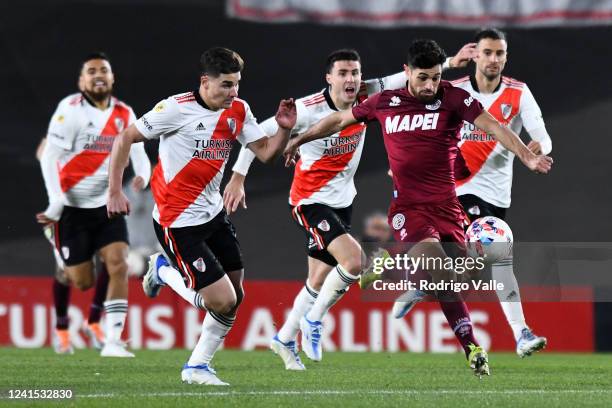 Lautaro Acosta of Lanus drives the ball against Julian Alvarez and Jose Paradela of River Plate during match between River Plate and Lanus as part of...