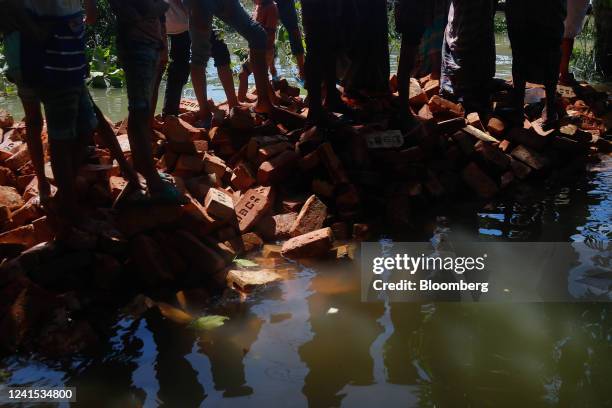 Disaster-affected residents wait on makeshift brick path to receive relief items, in Sylhet, Bangladesh, on Saturday, June 25, 2022. Bangladesh...