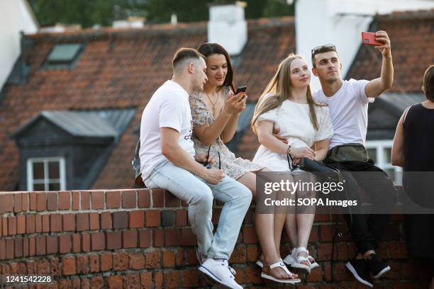 Couple take a selfie while sitting at the old walls near the Warsaw Barbican in Warsaw's Old Town. Daily life summer evening in Warsaw Old town after...