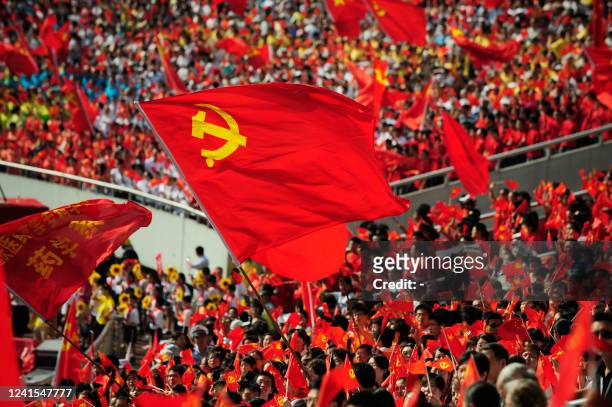 Chinese people wave flags of the Communist Party of China as they take part in the celebrations to mark the 90th anniversary of the ruling party's...