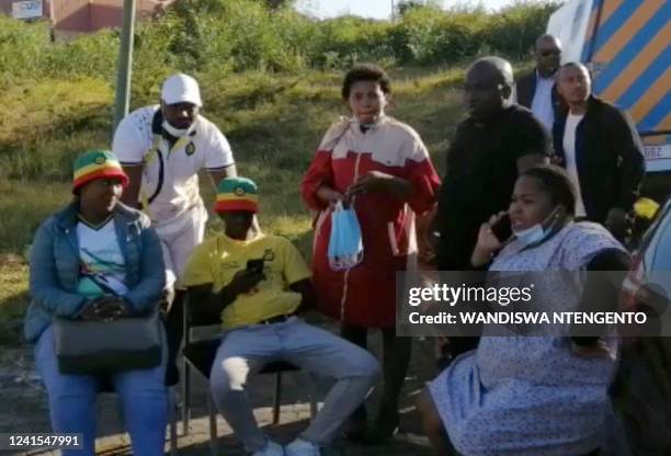 In this videograb taken from an AFP reporter, members of the community and family wait for news outside a township pub in South Africa's southern...