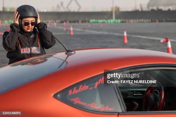 Picture taken June 26, 2022 shows Saudi woman Afnan Almarglani adjusting her helmet in front of her car at Derab circuit in the capital Riyadh. -...